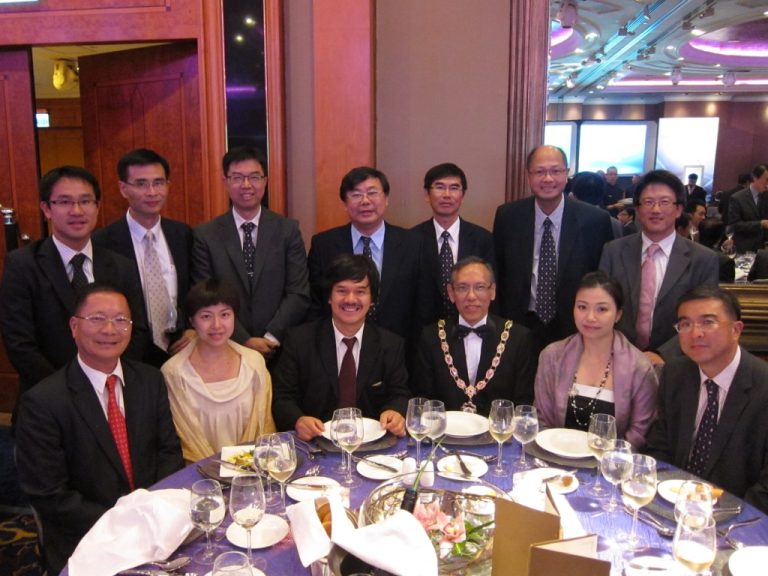Group of professionals in formal attire posing for photo at dining event
