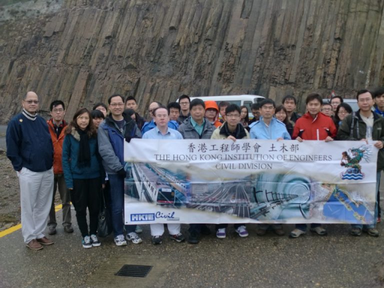 Group of people holding HKIE Civil Division banner in front of a rocky cliff face.