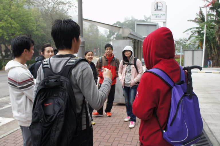 Group of students with backpacks gathered outdoors, one speaking to the others.
