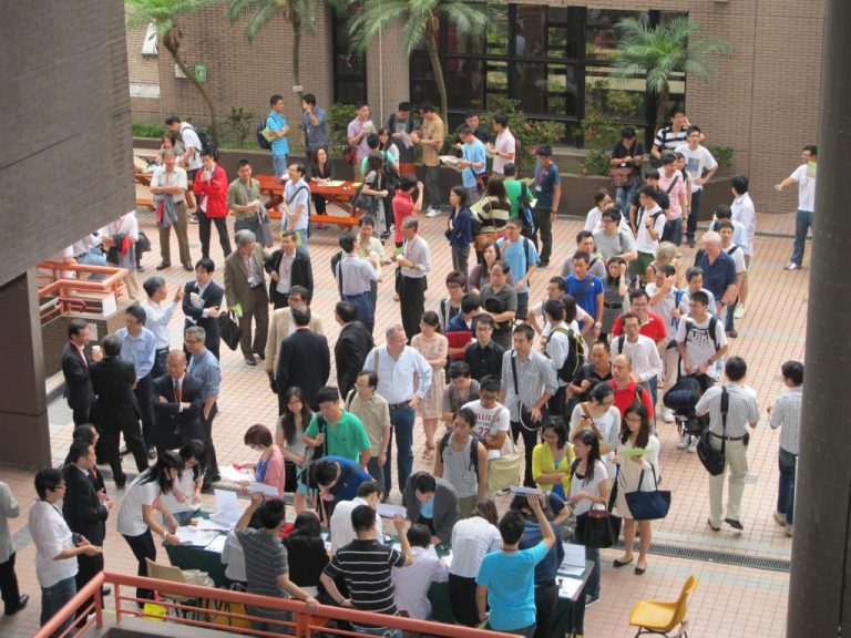 Crowd of people networking at an outdoor event in a courtyard.