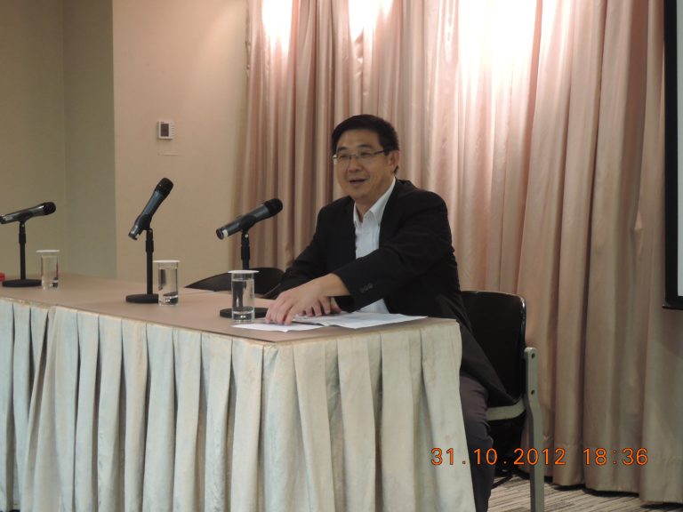 Person speaking at a table with a mic and glasses