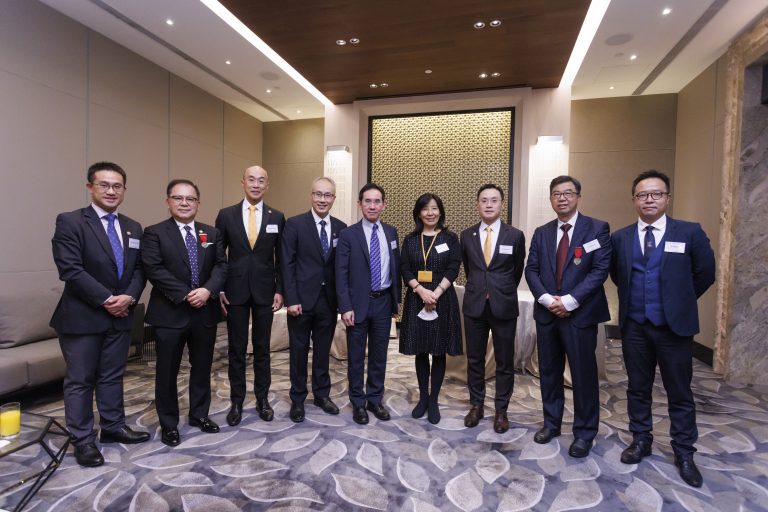 Group of eight professionals in formal attire posing for a photo at an event.