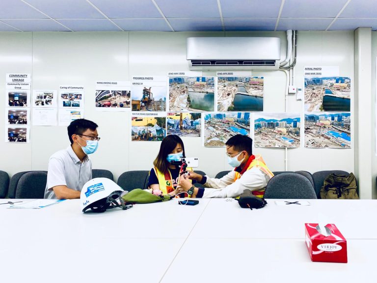 3 masked workers review photos in meeting room
