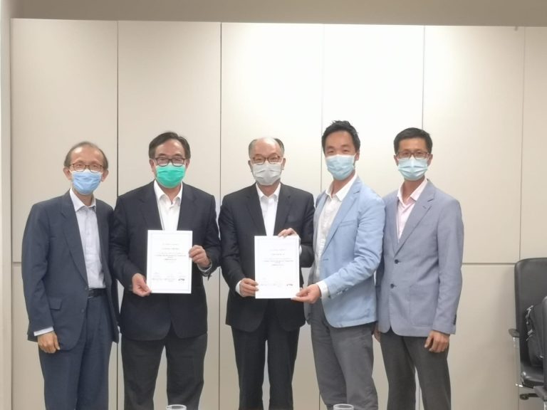 Five men in suits and face masks pose together, two holding certificates.