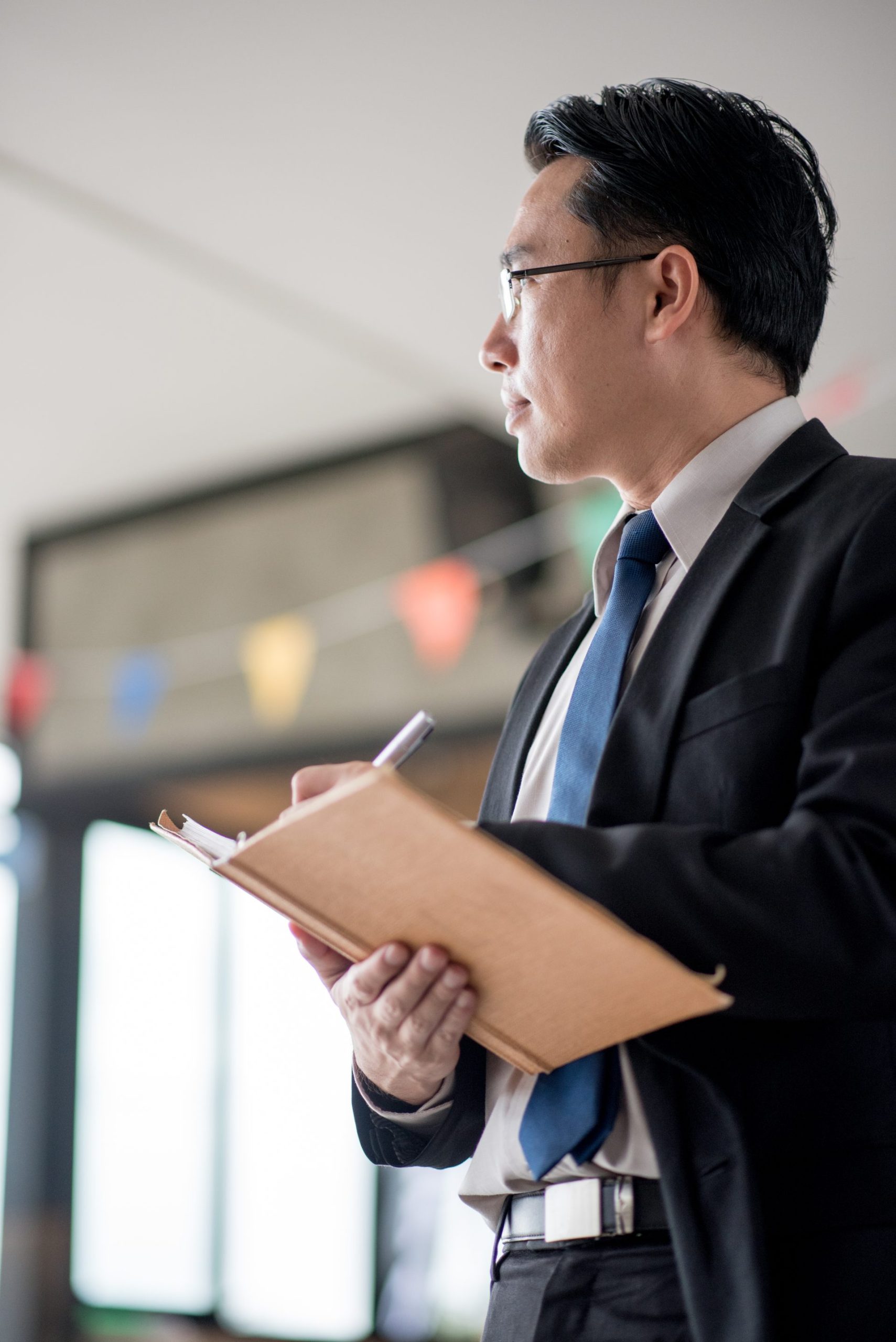 Businessman in suit writing in a notebook while standing in an office