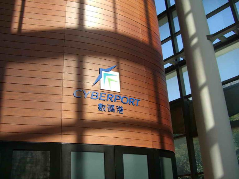 Cyberport logo on wooden building facade with glass windows and sunlight shadows.