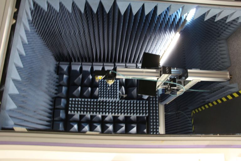 Acoustic testing chamber with sound-absorbing panels and measurement equipment.