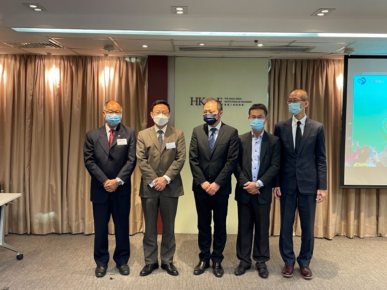 Five men in suits and face masks posing for a photo at an event.
