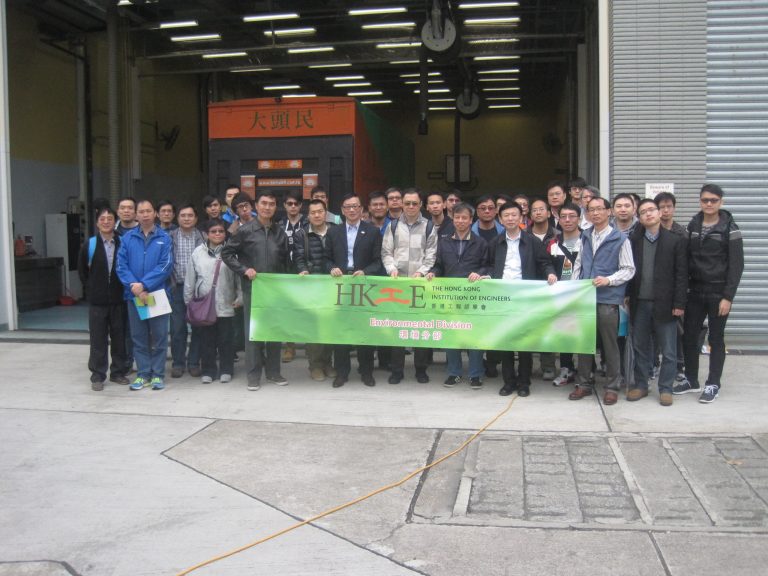 Group of engineers holding HKIE Environmental Division banner in front of warehouse.