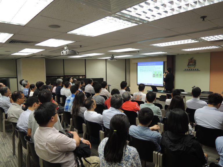 Audience attending a presentation in a conference room with a projector screen.