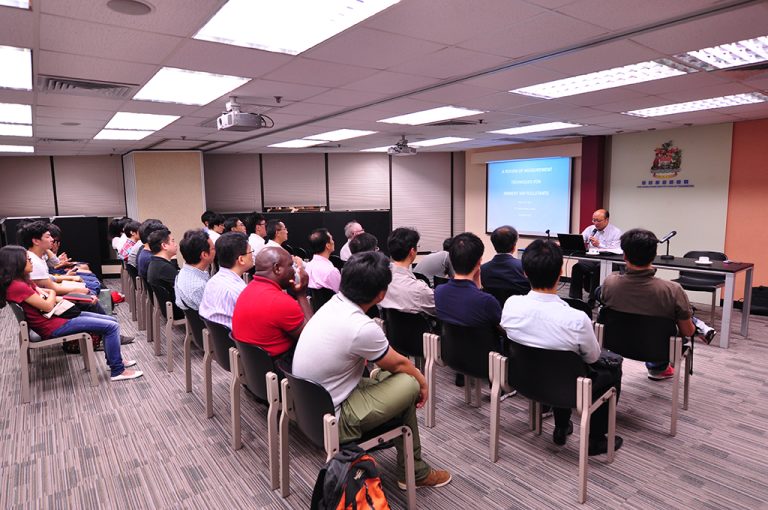 Audience attending presentation on air pollutant measurement techniques in conference room.