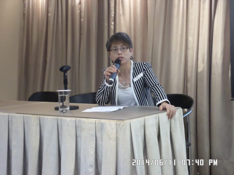 Woman speaking into microphone at table during event