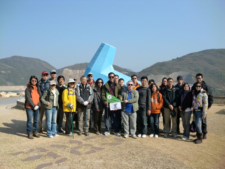 Group of hikers posing for photo with blue sculpture and mountains in background