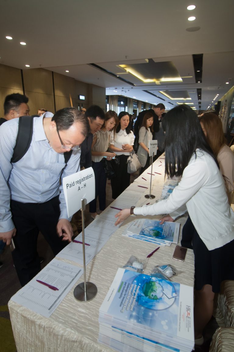 Attendees registering at a conference booth with paid registration signs and informational brochures.