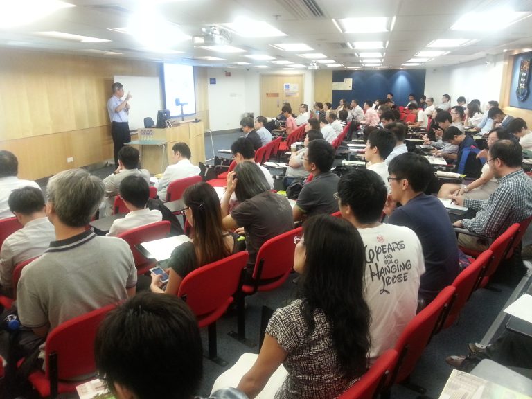Audience seated in lecture hall listening to presenter at front