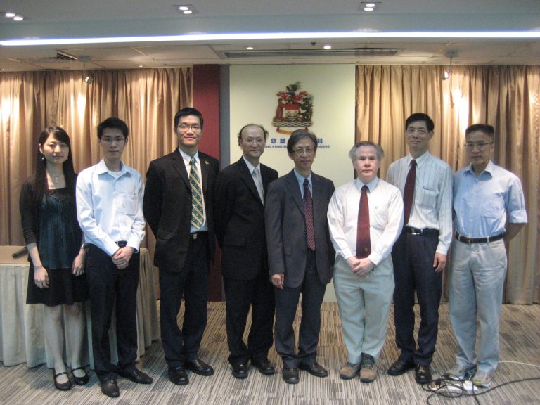 Group of eight professionals posing for a photo in front of Hong Kong Institution of Engineers logo.