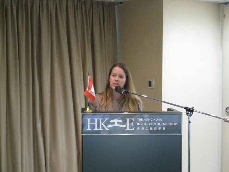 Woman speaking at podium with Hong Kong flag