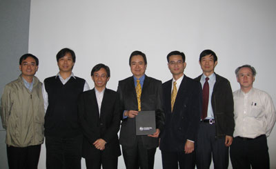 Group of seven men posing for a photo, one holding a box.