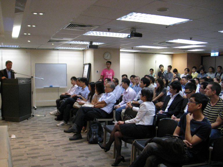 Audience attending presentation in conference room with speaker at podium.