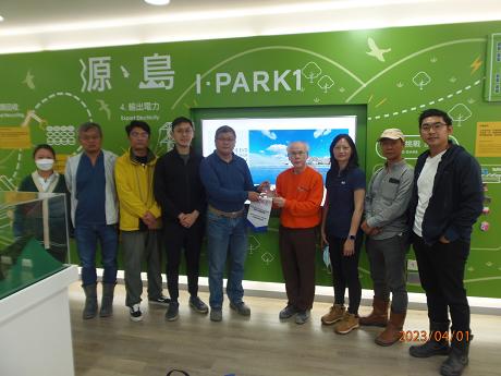 Group of people posing for photo in front of I-PARK1 green wall display