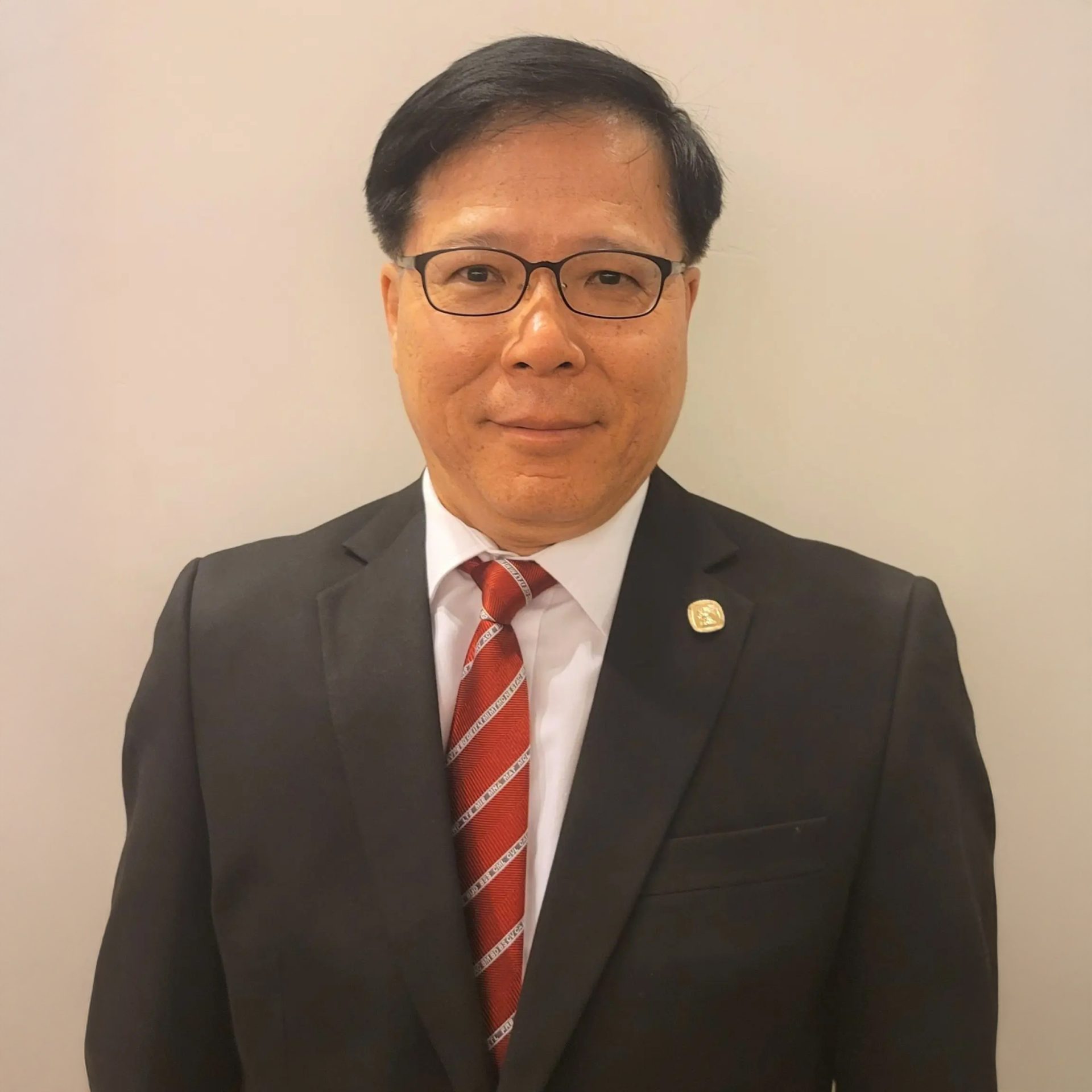 Man in suit and glasses wearing red tie with white text