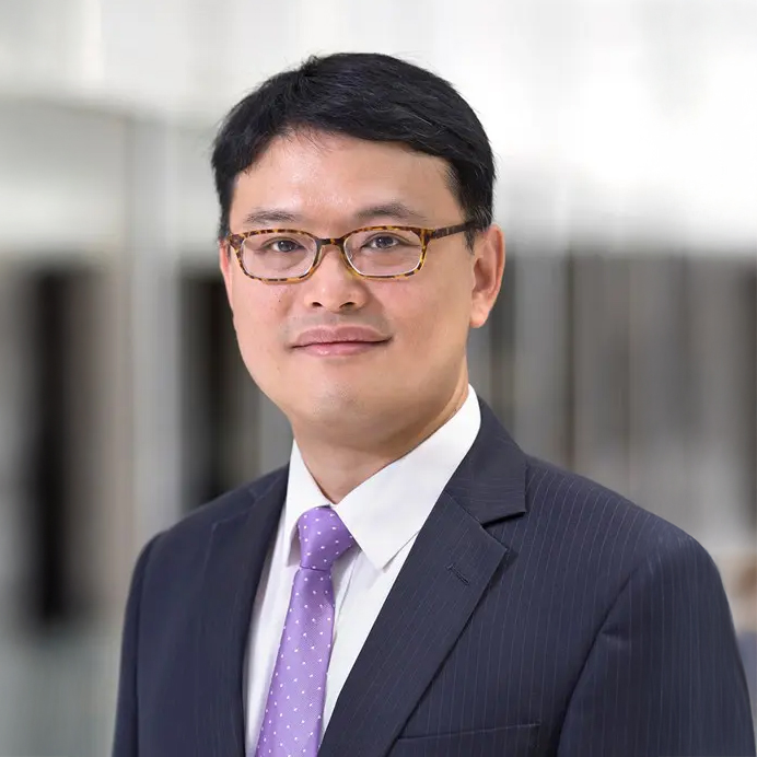 Professional headshot of Kelvin Tsang wearing glasses and a suit with purple tie.