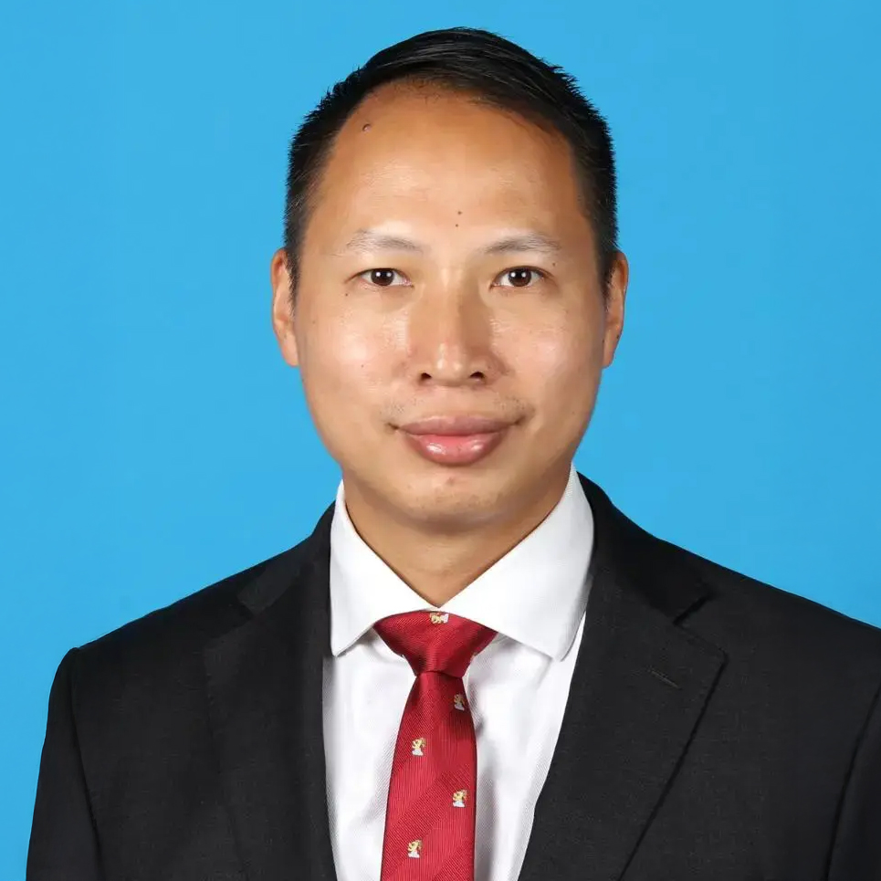 Man in black suit and red tie against blue background