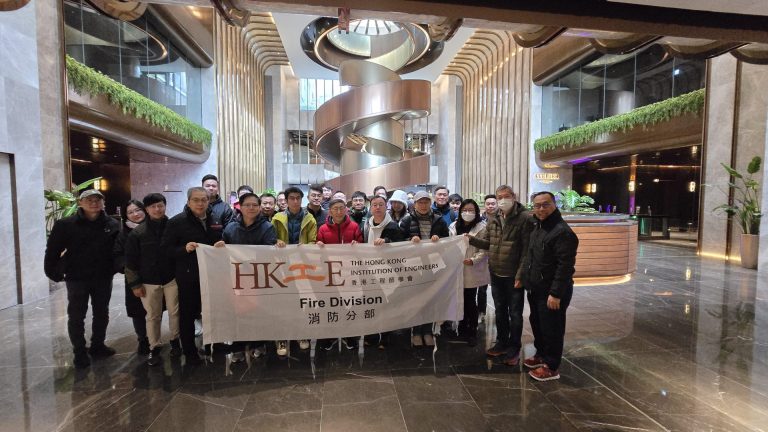 Group of engineers holding HKIE Fire Division banner in modern building lobby.