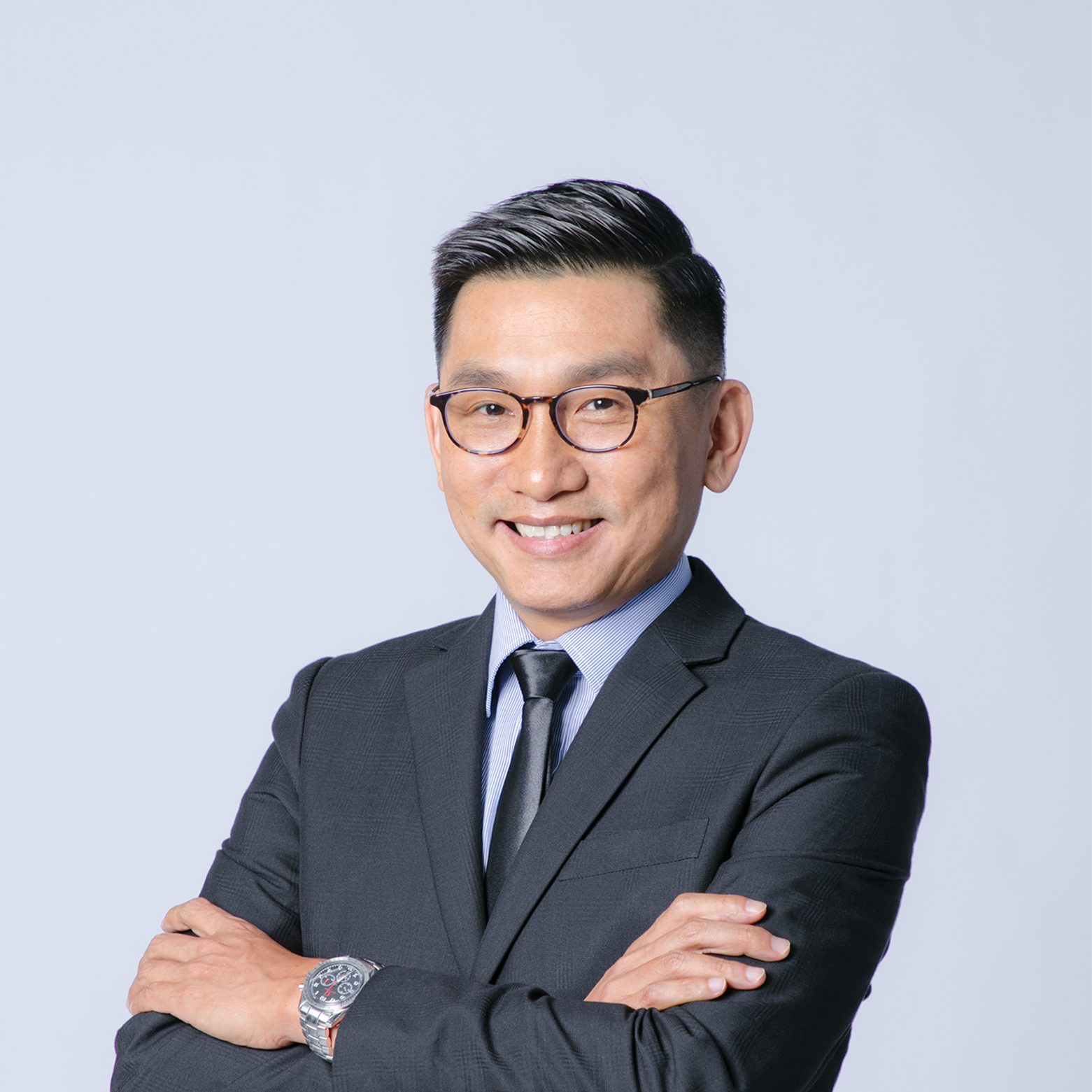 Professional man in suit and glasses smiling with arms crossed
