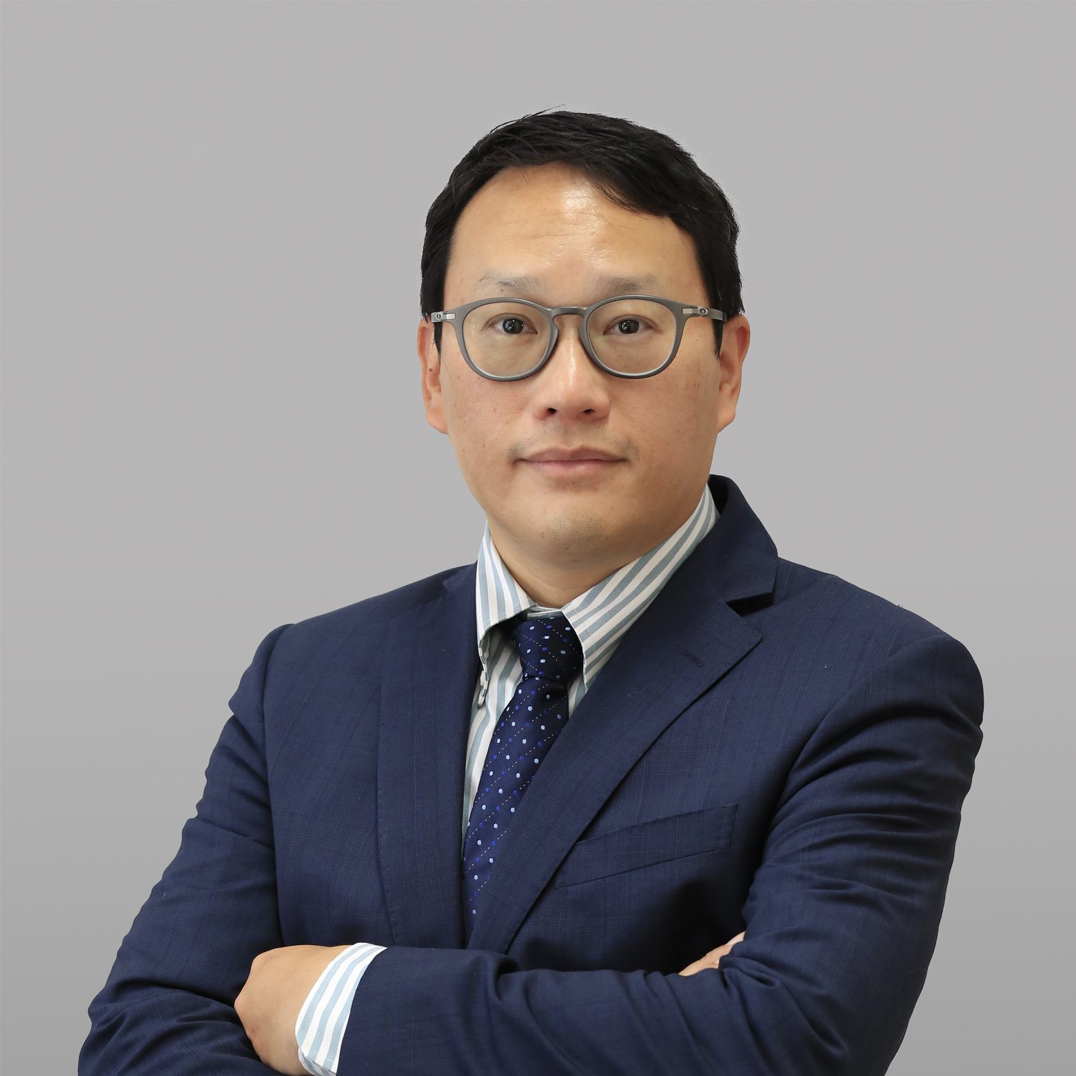 Man in glasses and suit with arms crossed, professional headshot