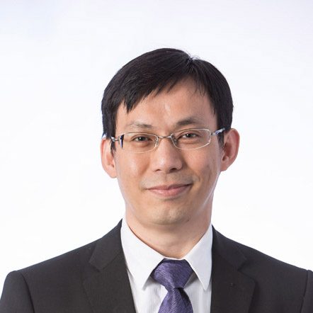 Headshot of a man wearing glasses and a suit with a purple tie.