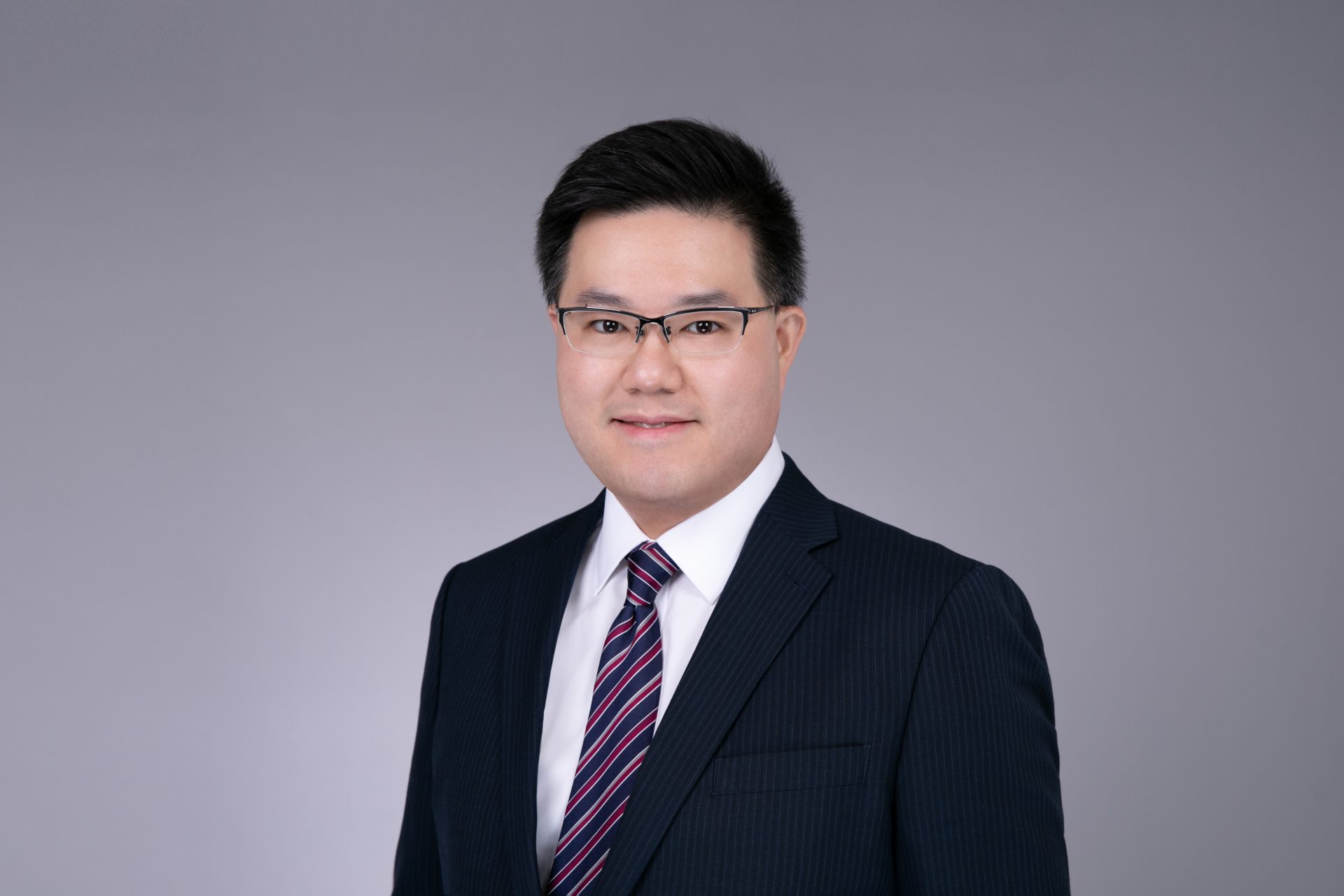 Professional headshot of a man in a suit and glasses