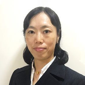 Portrait of a woman with dark hair wearing a dark blazer and white collared shirt.