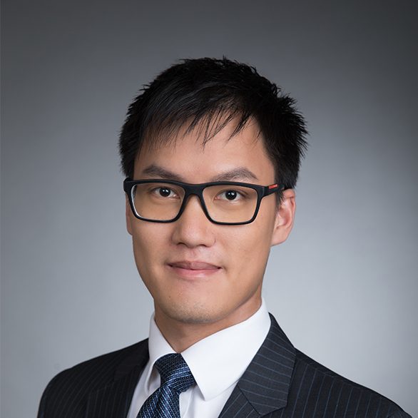 Professional headshot of a man wearing glasses and a suit.