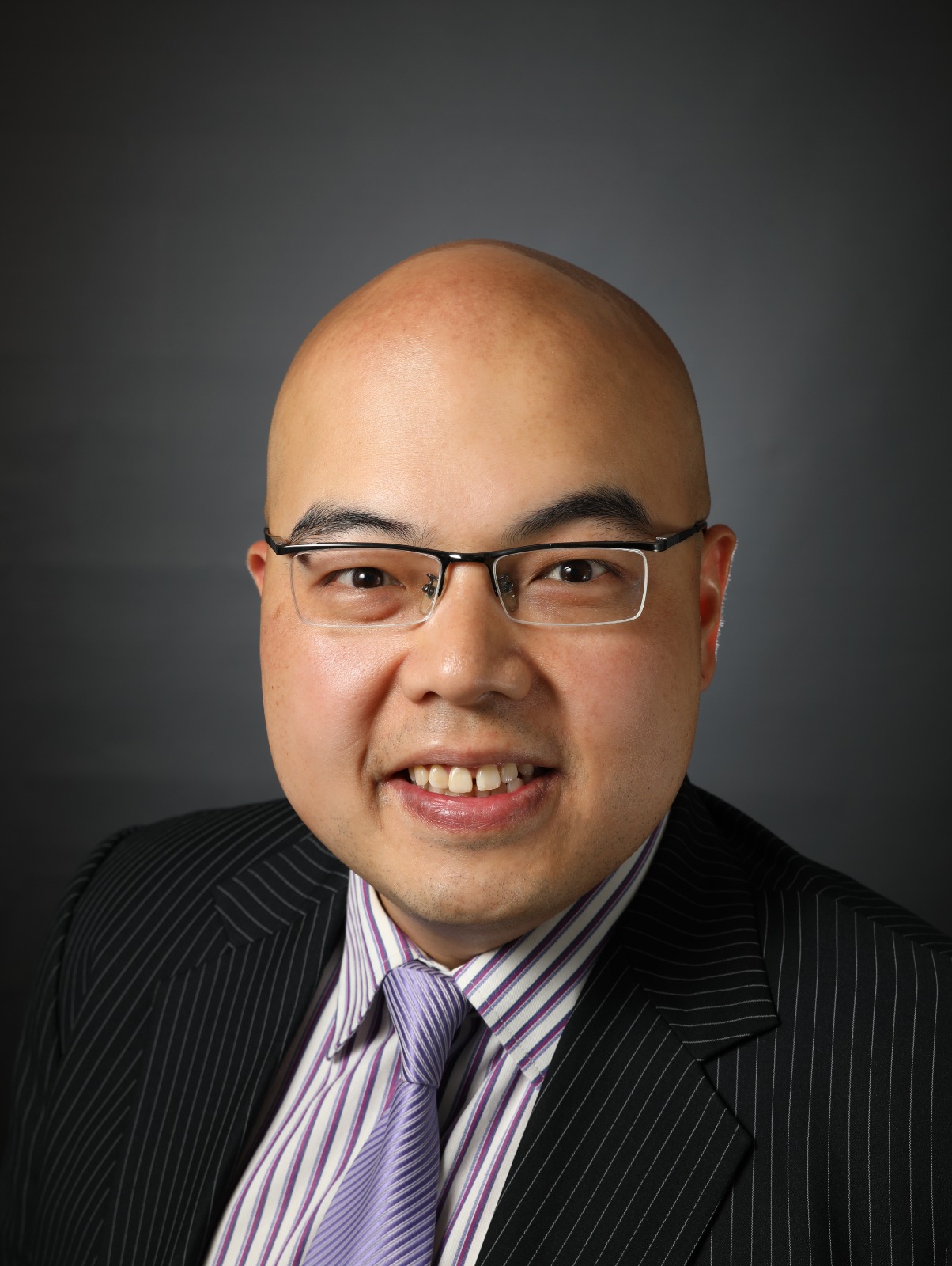 Headshot of a bald man with glasses, wearing a pinstripe suit and striped tie.