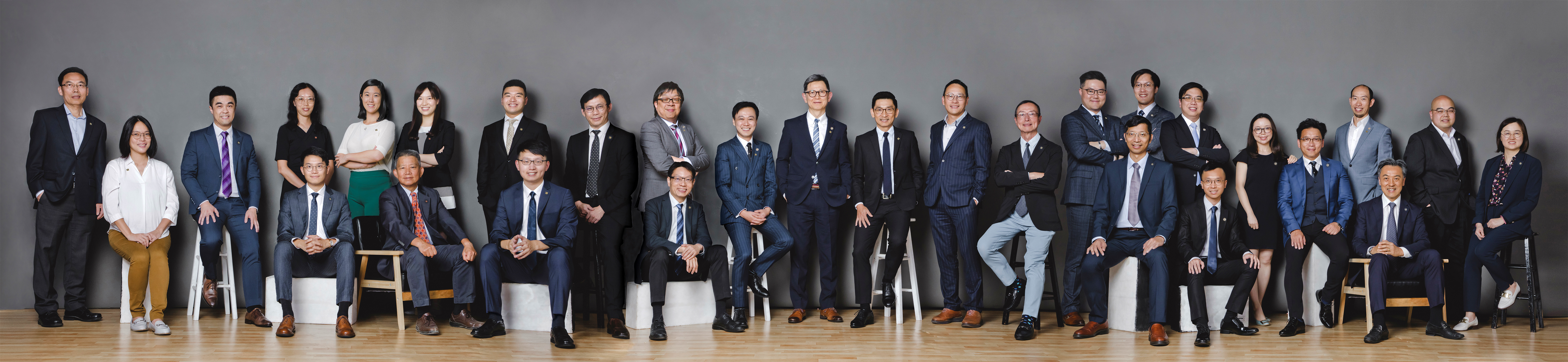 Group photo of professionals in business attire posing for a corporate team portrait.