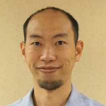 Portrait of a man with short hair and goatee wearing a light blue shirt.