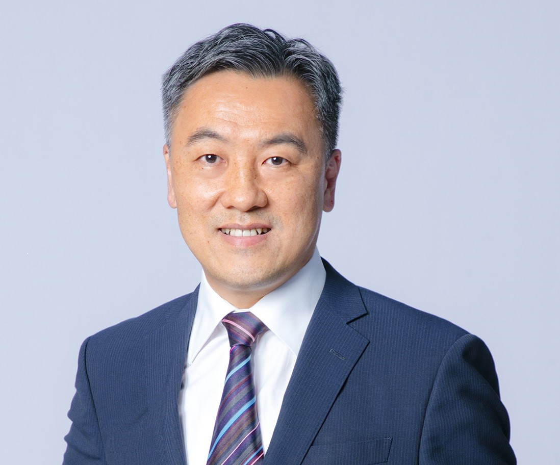 Professional headshot of a smiling man in a suit and tie.