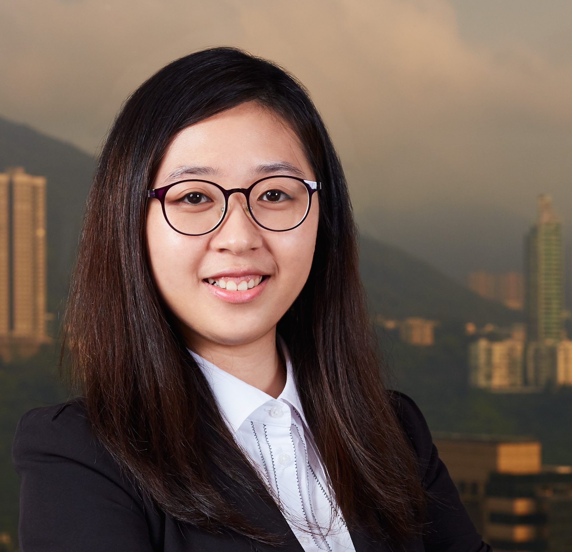 Professional headshot of a smiling woman with glasses wearing a suit and white shirt.