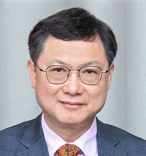 Portrait of a man with glasses wearing a suit and patterned tie.