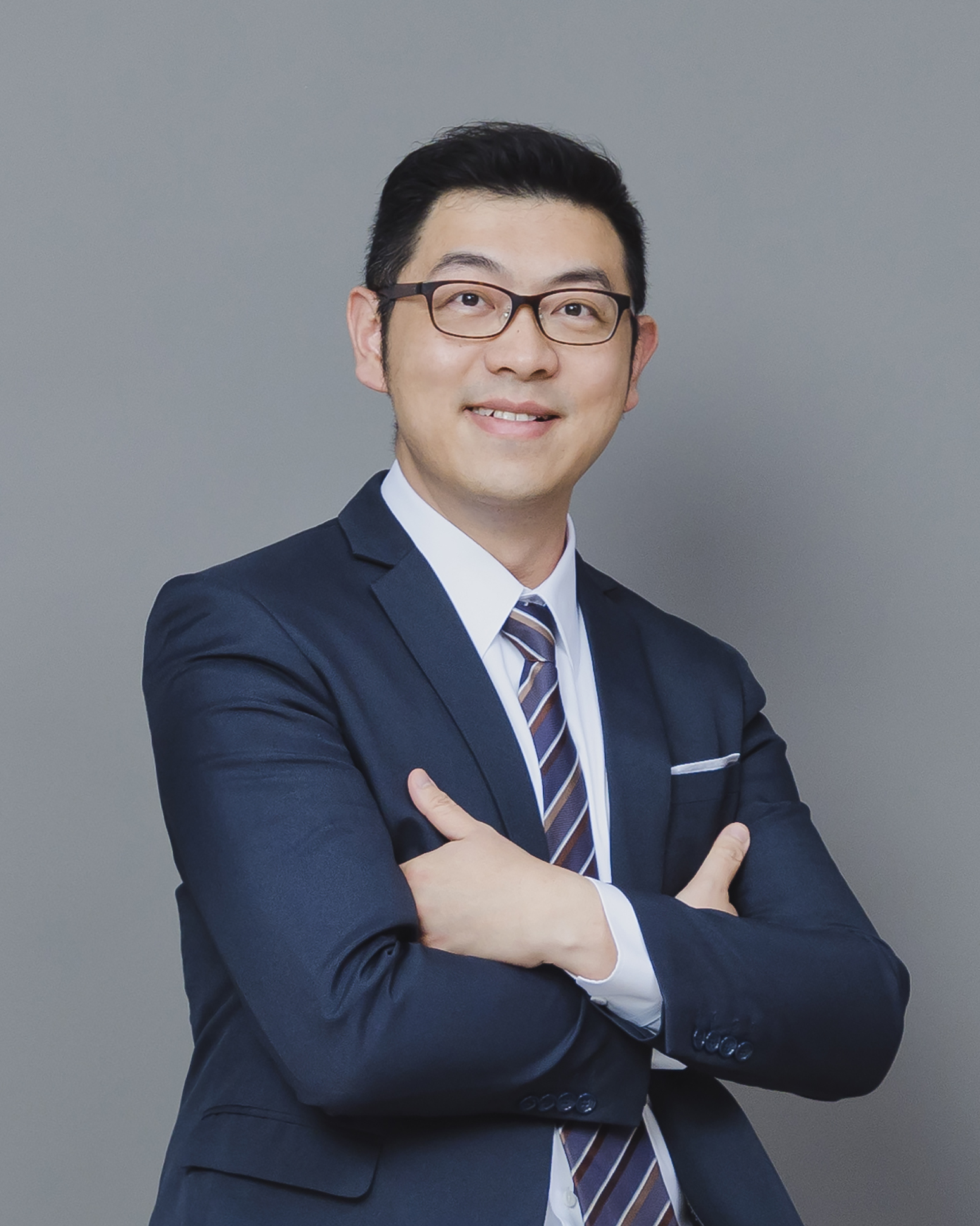 Professional man in suit and glasses with arms crossed, smiling at camera