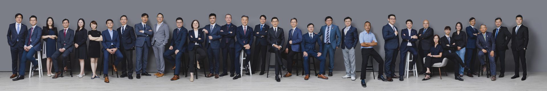 Group photo of professionals in business attire posing for corporate team portrait.