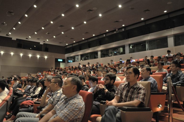 Audience seated in tiered auditorium listening to presentation