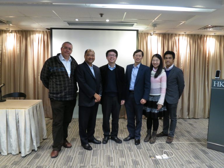 Six people posing for a photo in a conference room with curtains and a podium.