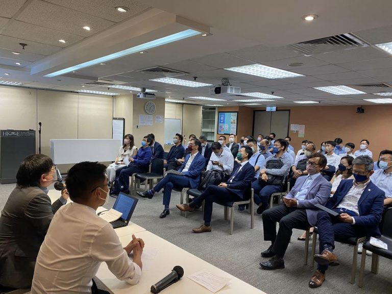 Audience attending a presentation in a conference room wearing face masks.