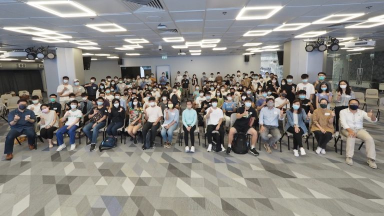 Group of people wearing masks posing for a photo in a conference room.