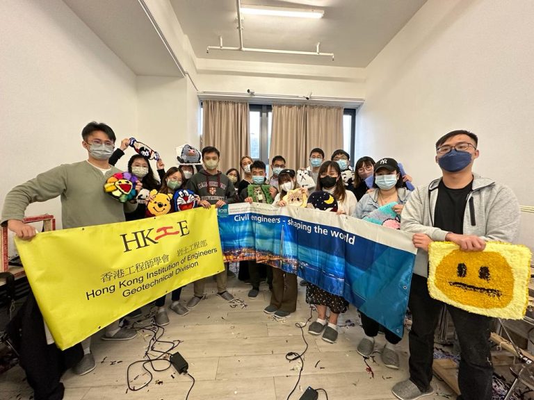 Group of civil engineers holding banners and plush toys at an event