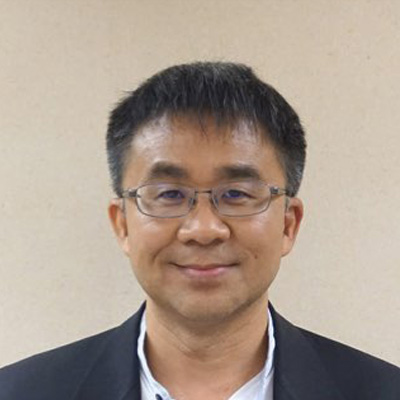 Portrait of a smiling man with glasses wearing a dark suit jacket.