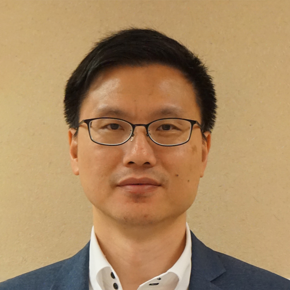 Headshot of a man with glasses wearing a suit and white shirt.