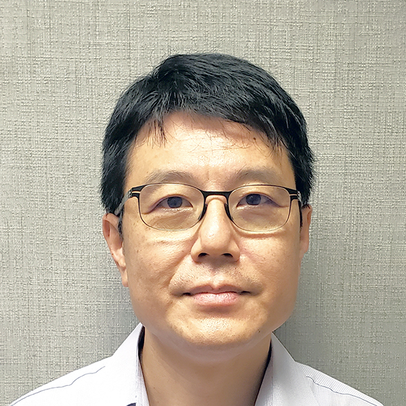 Man with glasses and short dark hair wearing a light-colored collared shirt.